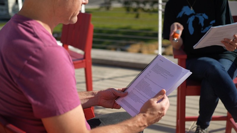 Actor holds a spiral-bound script in their hands
