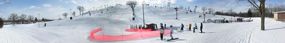 Wide angle lens view of downhill ski runs with people on skis