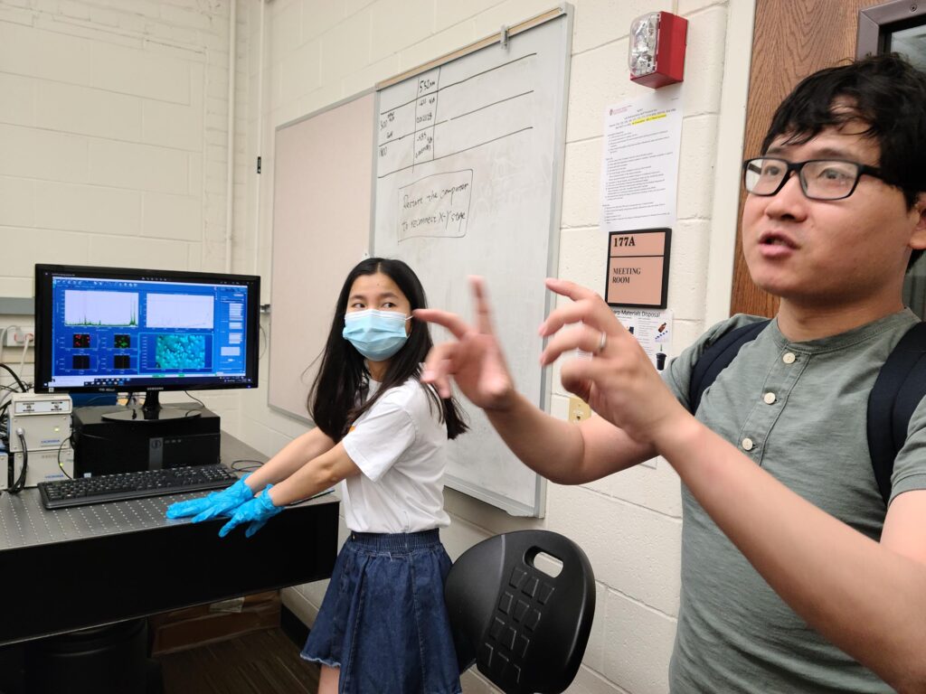 Haoran Wei and Ziyan Wu stand in a lab with a computer displaying images of samples.